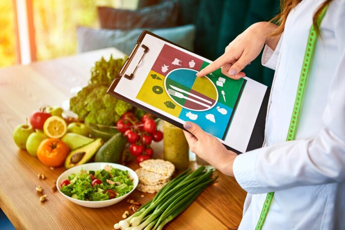 Holding schematic meal plan for diet with various healthy products on the background. Weight loss and right nutrition concept. Eating food pyramid
