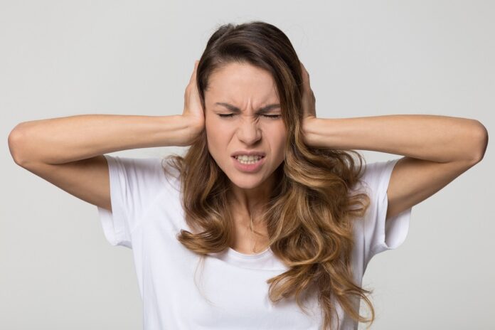 Annoyed stressed woman covering ears with hands feeling ear pain