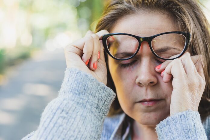 Woman rubbing her eye outdoors